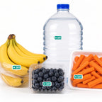 Four grocery items on a white background: bagged bananas, bottled water, packaged blueberries, and carrot sticks. A small rectangular green-star Safe Food allergy sticker is placed on each package.